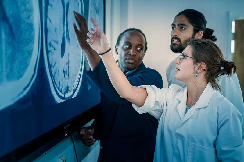 Students discussing a CT scan of a brain with Professor Peter Bazira