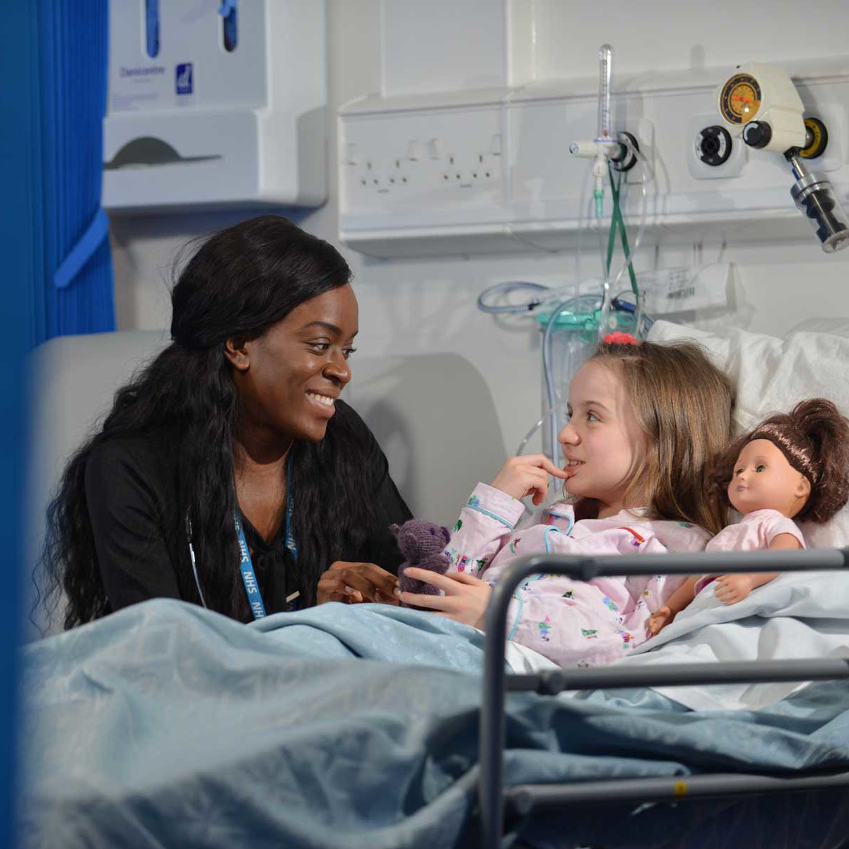 Medical student talking to a child patient on a hospital ward