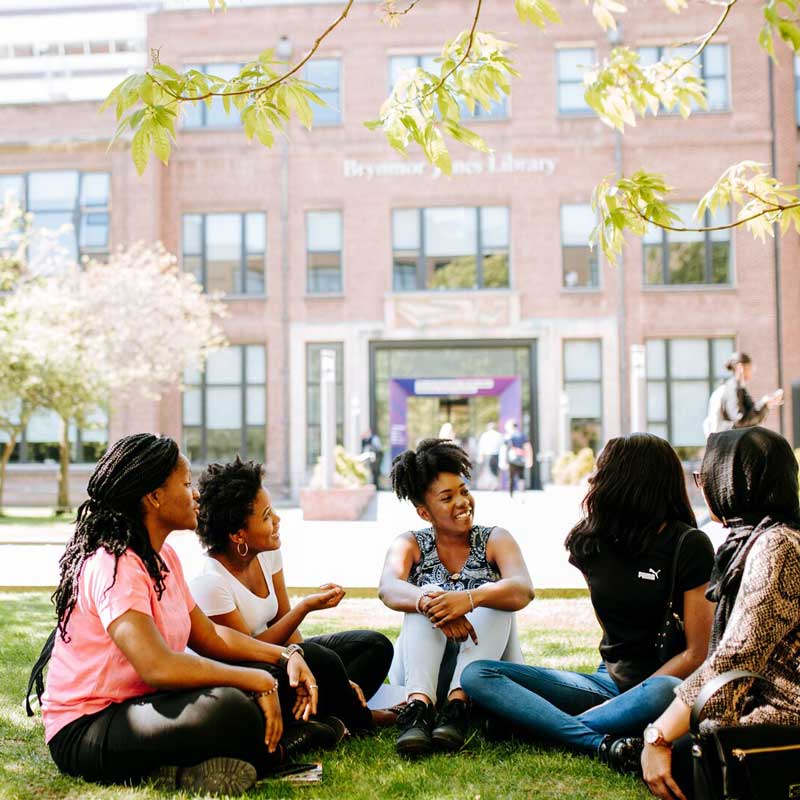 Students on grass by the Library
