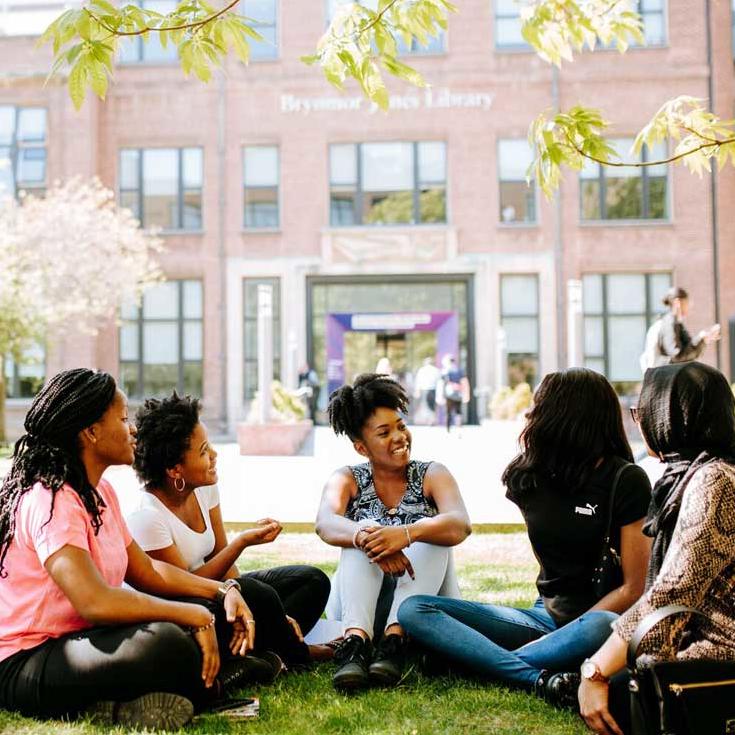 Students on grass by the Library
