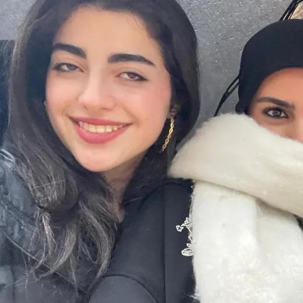 Three students take a selfie under an umbrella