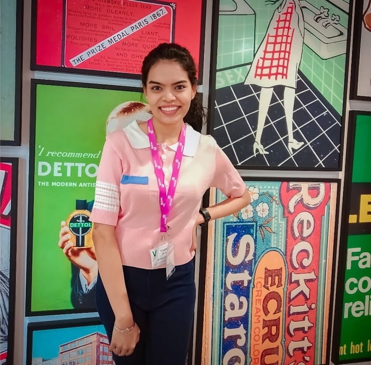 Pharmacology student Kiran posing in front of a colourful poster display