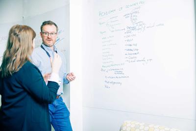 Two members of the Academy of Primary Care in a discussion by a whiteboard
