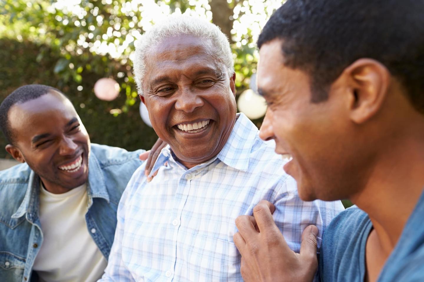 Three men of different generations laughing in a garden