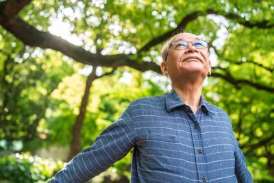 Man with arms raised taking a deep breath in nature