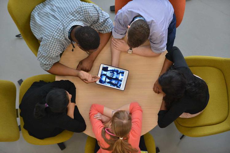 View from above of Medicine students in the Allam Medical Building, collaborating around an iPad displaying X-rays